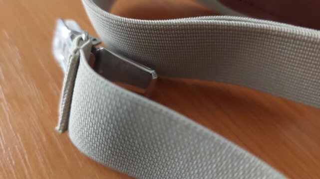 Detailed view of beige elastic suspenders with metal clips