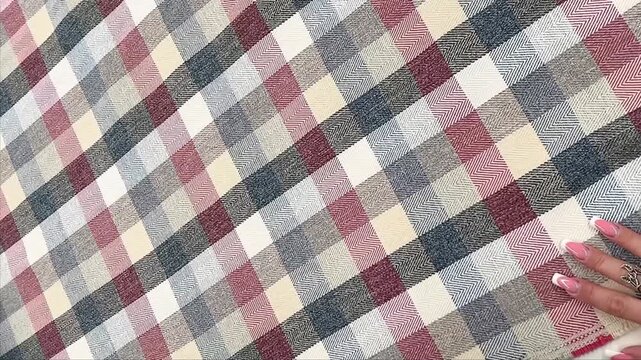 Heavyweight woven plaid fabric features a detailed herringbone texture in a palette of burgundy, navy blue, beige, and grey shades which provides a versatile and durable surface for upholstery.