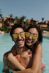 Obraz premium Couple laughing and embracing while standing in pool
