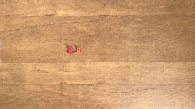 child hands taking away one clip from three colorful clips leaving two on wooden table slow motion 4K