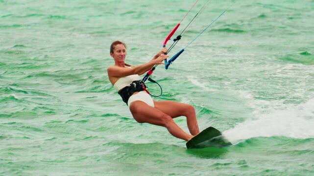 Sports woman kitesurfing in ocean in white bikini. Extreme summer sports