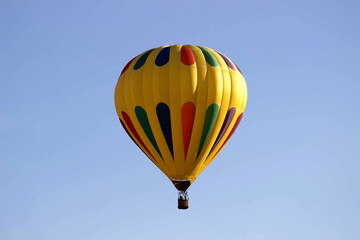 Obraz premium Yellow hot air balloon with colorful teardrop accents in clear sky