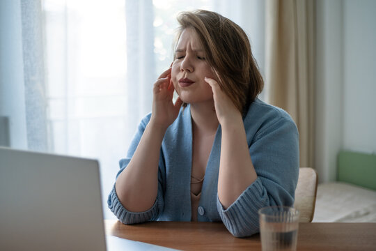 Digital burnout plus size woman suffering headache near laptop, remote work stress, migraine, screen fatigue, mental health, wellness at home.