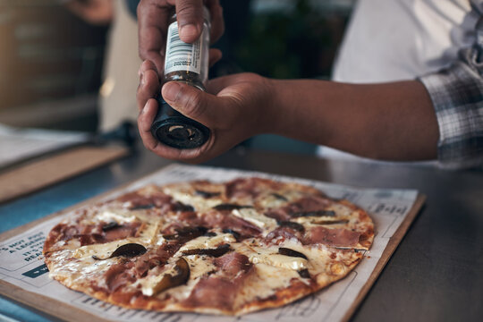 Hands, person and pizza with spice at restaurant for meal prep, ingredients and Italian recipe. Chef, cooking and pepper seasoning for cuisine flavor, healthy food and culinary skills for takeaway