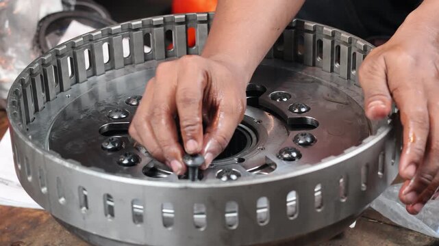 A close-up, static shot of a mechanic's hand carefully inserting and threading a bolt into a heavy-duty industrial piston assembly. Demonstrating precision manual work.