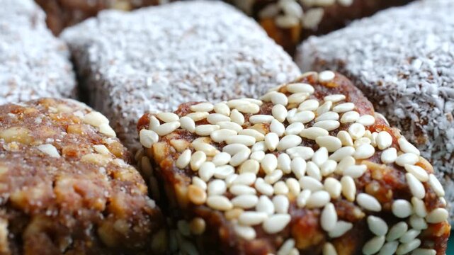 Delicious and healthy assortment of homemade energy bars with dates, coconut flakes, and sesame seeds in a detailed macro shot. Healthy homemade dates coconut and sesame energy bars