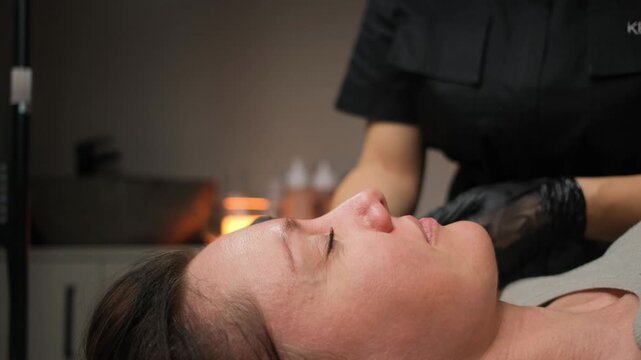Professional cosmetologist performs an eyebrow waxing treatment on a female client in a beauty parlor