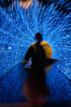 Abstract motion blur of woman silhouette  in glowing blue light tunnel with golden energy core
