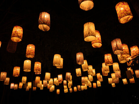 Warm glowing paper lanterns hanging in dark night sky, festive illumination and cultural celebration atmosphere with soft golden light