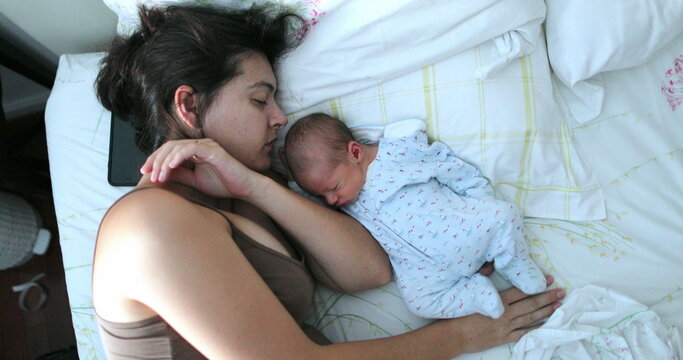 Baby and mother sleeping together in bed
