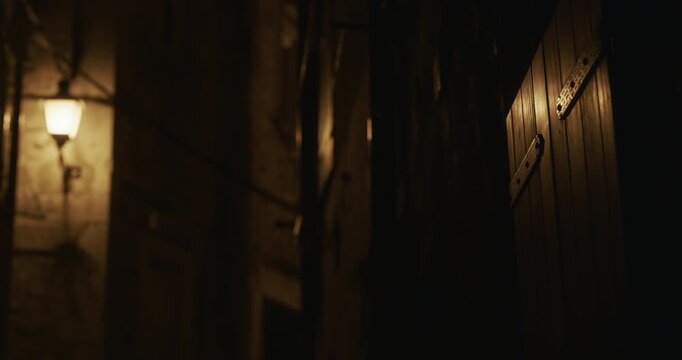 Wooden window shutters and wall lamp in narrow street at night