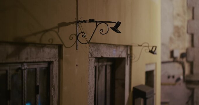Decorative metal lamp brackets on building facade at night
