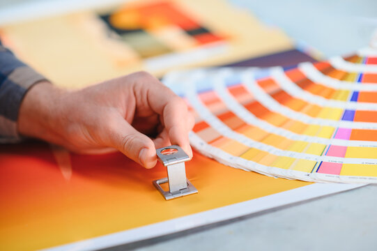 Printer hand checking color swatches with loupe