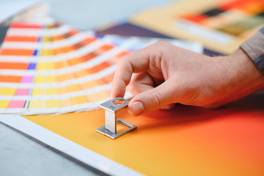 Print worker inspecting color quality using a loupe