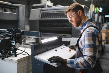 Obraz premium Print factory operator working with offset machine controls