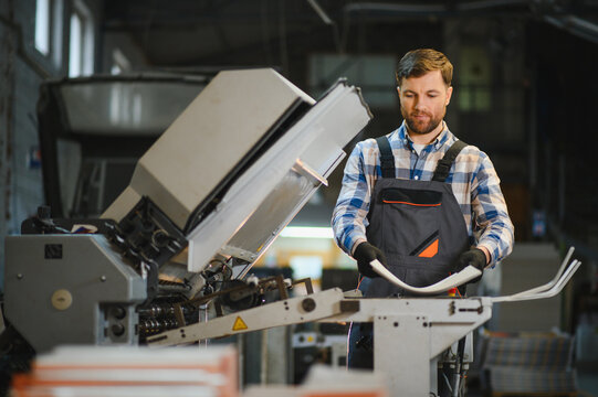 Worker operating industrial machine in a printing house