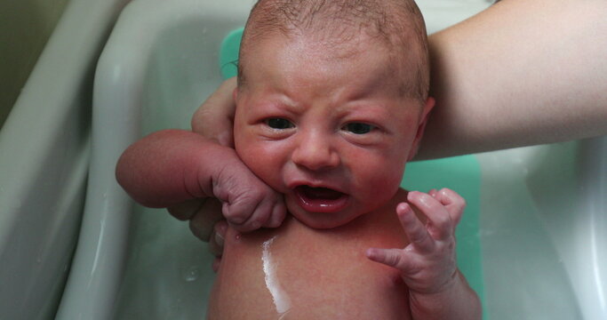 Washing newborn baby bathing in warm water fro the first time