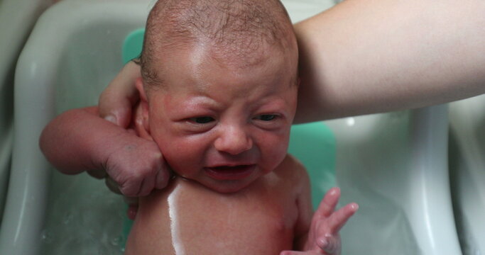 Washing newborn baby bathing in warm water fro the first time