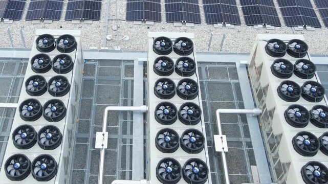 Aerial of hyperscale data center with cooling ventilators and solar panels on roof