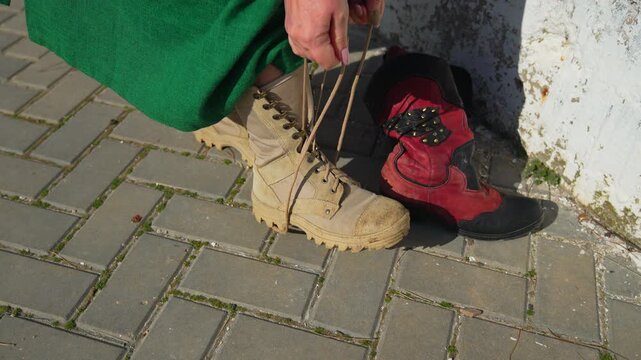Boots lacing woman a woman in a green dress ties her tan tactical boots while sitting on a brick sidewalk outdoors