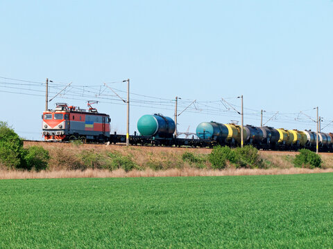 Freight train with oil tank wagons traveling through rural countryside