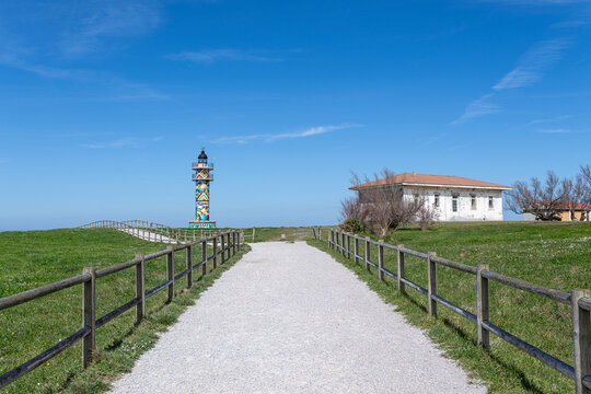 Colorful ajo lighthouse standing on coastal cliff overlooking the sea, bareyo, spain faro de ajo punta del caballo