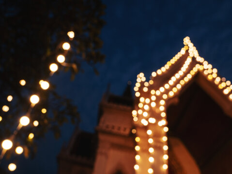 Defocused golden lights on Thai temple at night with warm bokeh and traditional architecture atmosphere