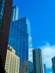 Fototapeta premium Buildings rise in a city skyline under a clear blue sky during the daytime showcasing glass fa ades and city life
