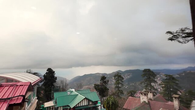 Colorful rooftops and distant mountains are seen through a window.