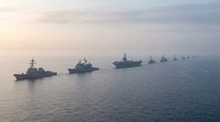 Obraz premium Naval fleet of warships sailing in formation across calm ocean waters during early morning fog. Concept of military power, naval operations, aircraft carrier deployment, maritime security