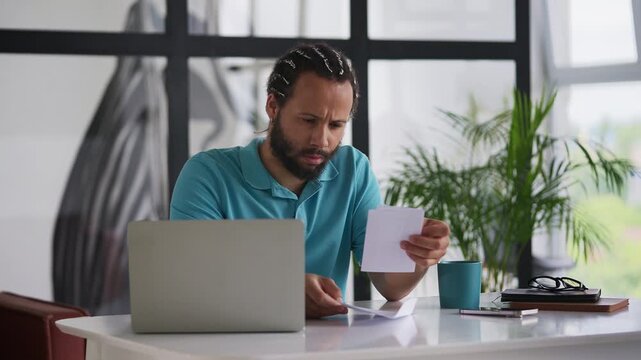 African American man reading a bad news letter at home, feeling disappointed