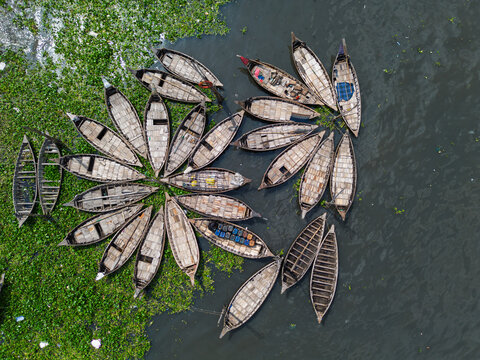 Aerial view of wooden boats arranged in a circular pattern on the Buriganga River with green water hyacinths Dhaka, Dhaka Division, Bangladesh.