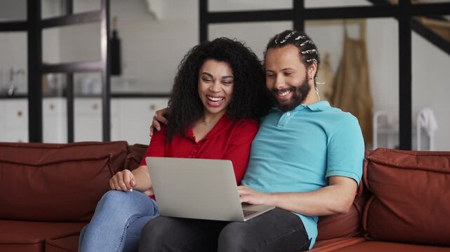 Loving African American couple choosing a pet on laptop, planning to adopt a dog