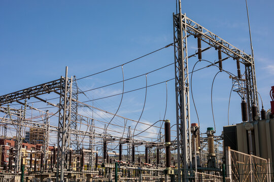 Close up view of high voltage electric substation with insulators, wires and steel structures against clear blue sky, no power concept