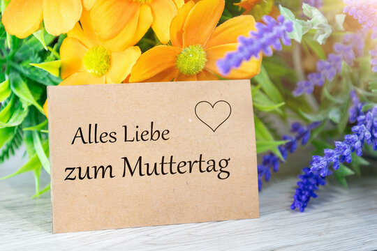 Liebevoller Muttertagsgru&szlig; auf einer Karte, umgeben von bunten Fr&uuml;hlingsblumen (mit hinzugef&uuml;gtem Text ALLES LIEBE ZUM MUTTERTAG)