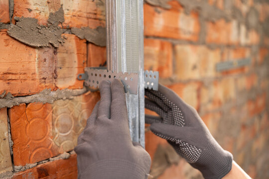 Close-up of construction worker Installation of metal profiles on brick walls. Repair, renovation and home