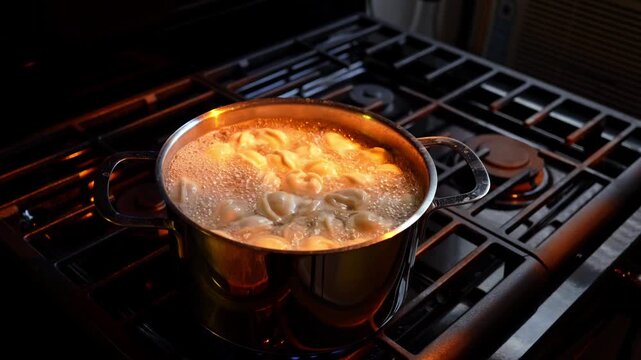 Tortellini Boiling in Pot With Gas Flame. Close view of tortellini boiling in metal pot on gas stove with blue flame and dark background.
