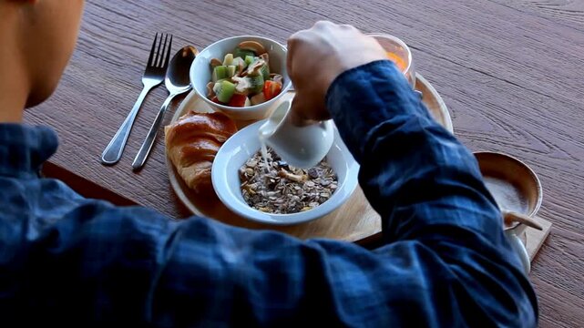 Person enjoying a healthy breakfast with cereal and fresh vegetables on a wooden table