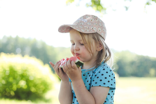 cute little girl eating watermelon outdoors in summertime. Child and watermelon in summer. 