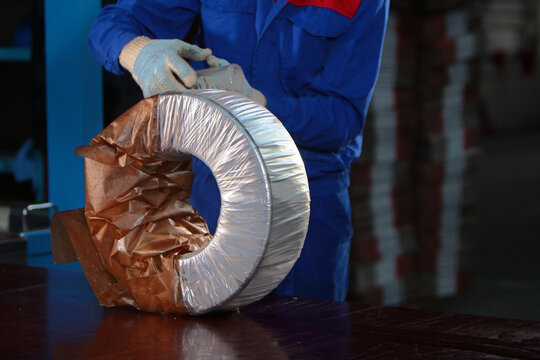 Worker packs finished bearing. Finished products at factory. Oiled parchment for packaging metal products. Workshop at heavy industry plant. Heavy industry.