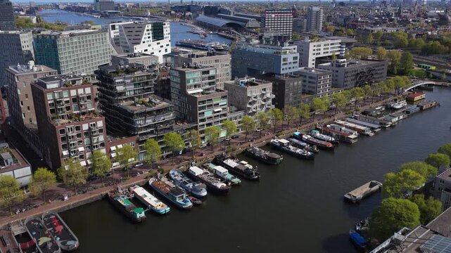 Westerdok Amsterdam skyline showing modern architecture, houseboats on canals, Centraal Station, revealing city's unique urban landscape from above during springtime