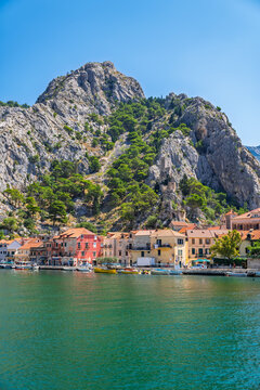 Panoramic view of the coastal town of Omis, Croatia, situated at the base of massive limestone cliffs where the Cetina River meets the Adriatic Sea