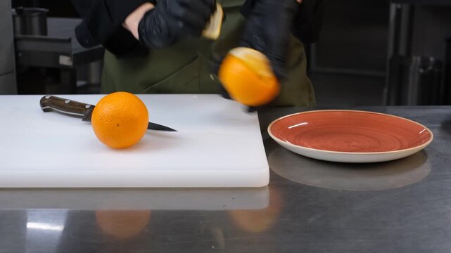 Chef in restaurant kitchen peeling orange

