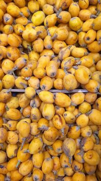 Fresh Loquat Fruits Piled in Wooden Crates at Supermarket, Vertical Video