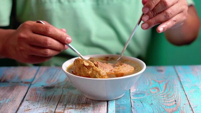 Indonesian is eating bakso gajah (bakso jumbo, giant meat ball). Bakso is one of indonesian street food.