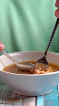 Indonesian is eating bakso gajah (bakso jumbo, giant meat ball). Bakso is one of indonesian street food.