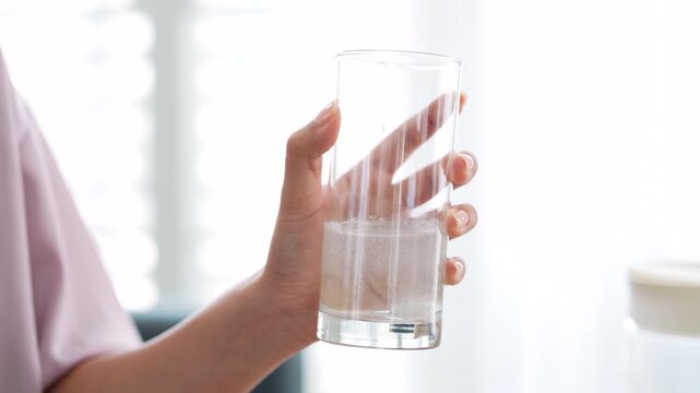 Young woman at home in morning. putting Effervescent tablet or  Fizzy tablet into glass of water.
