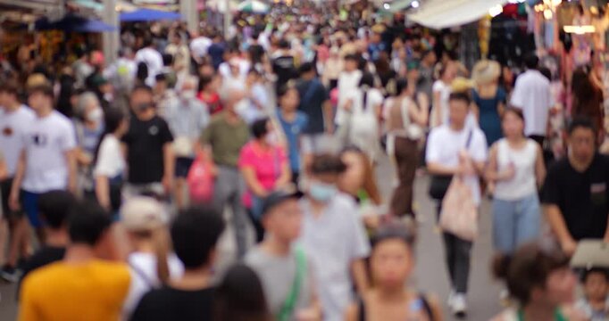 Anonymous crowd of shoppers moving through Bangkok Chatuchak weekend market, blurred slow motion shot ensures footage is suitable for commercial usage. Many people at wide pedestrian alley