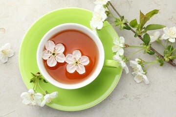 Plakat Aromatic tea in cup and flowers on light grey table, flat lay