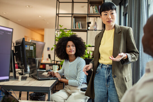 Female team leader mentoring coworker in modern open office
